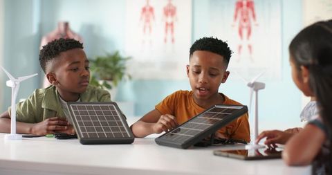 African american kids collaborating on solar panels and wind turbines in stem lab