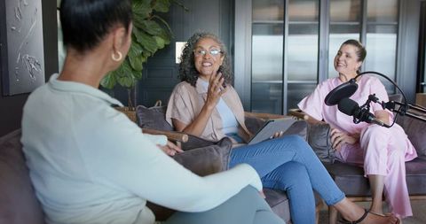 Women hosting relaxed podcast conversation in cozy modern home studio living room