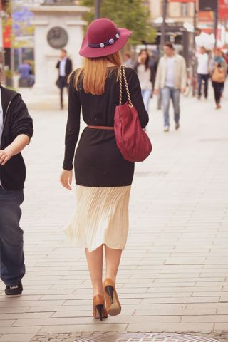 Stylish woman with red handbag walking in urban street