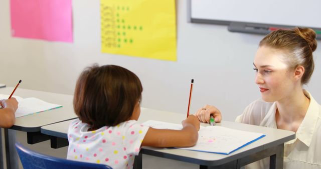 Young Student Receiving Assistance from Teacher in Classroom - Download Free Stock Images Pikwizard.com