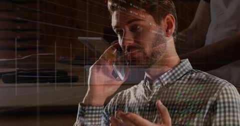 Business analyst talking on smartphone while reviewing financial charts and data overlay
