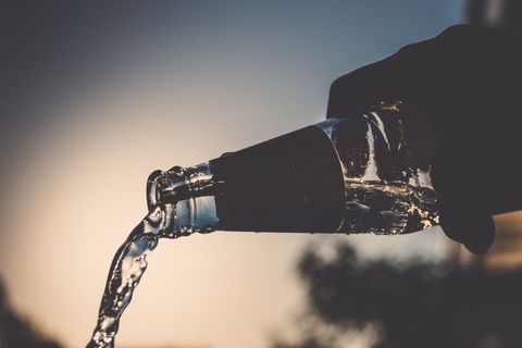 Silhouette of Bottle Pouring Skyward Against Sunset