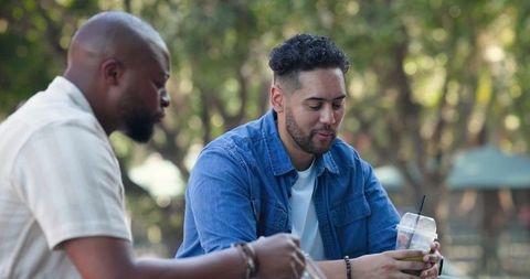 Two men chatting outdoors holding takeaway drinks casual urban friendship lifestyle