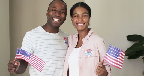 Diverse couple celebrating voting with american flags