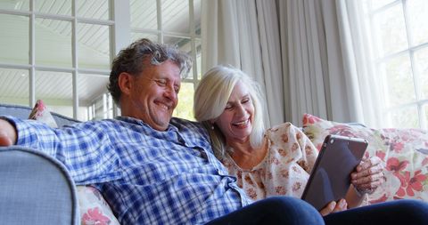 Happy Senior Couple Enjoying Tablet on Sofa at Home - Download Free Stock Images Pikwizard.com
