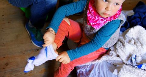 Caucasian toddler putting on socks with parent at home