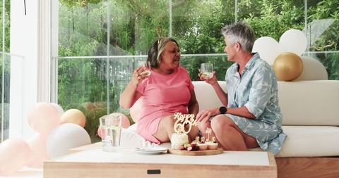 Senior Lesbian Couple Celebrating Birthday with Cake and Drinks