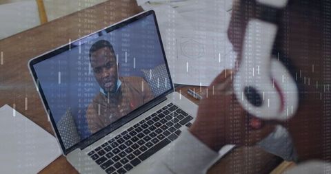 Hosting remote video call on laptop with focused professional wearing white headphones