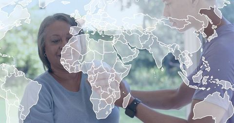 Caregiver Adjusting Wearable Health Monitor on Senior Woman with Global Health Map Overlay