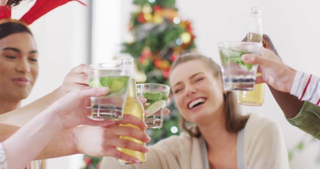 Group of friends enjoying a Christmas party, laughing and toasting with drinks. Great for holiday promotional content, festive event invitations, or social media posts focused on celebration and togetherness.