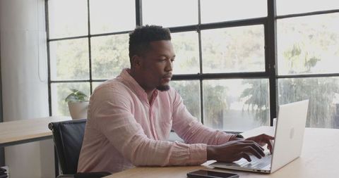Focused Young Professional Man Working on Laptop in Bright Office