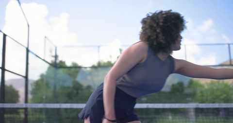 Woman lunging and reaching for ball on tennis court near net in sunny outdoor action