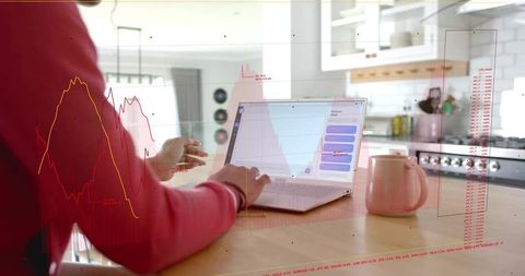 Woman typing on laptop at sunlit kitchen island with data overlays for remote work