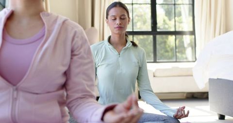 Diverse women practicing meditation at home, yoga mindfulness, cozy serene morning routine