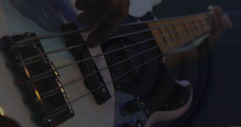 Musician playing bass guitar on dimly lit stage