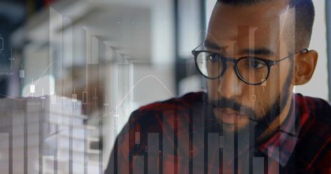 Analyst reviewing financial market charts on transparent display while focusing on data
