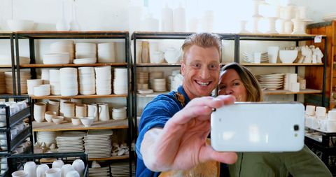 Happy couple taking selfie in pottery workshop