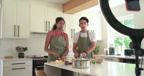 African American Couple Filming Cooking Tutorial in Bright Modern Kitchen with Ring Light