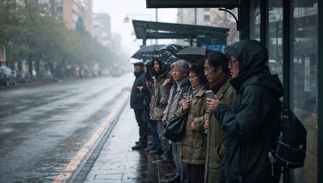 Rainy city commuters waiting at bus shelter checking phones under umbrellas, moody transit