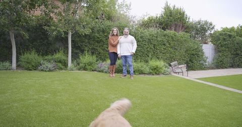 Happy Couple Enjoying Tranquil Backyard with Playful Dog