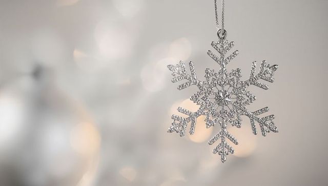 Hanging silver snowflake ornament with sparkling crystals and warm bokeh lights