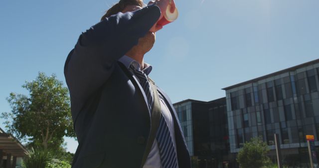 Caucasian businessman standing on skateboard, drinking water on sunny day - Download Free Stock Photos Pikwizard.com