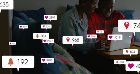 Smiling couple using laptop on cozy sofa with social media notifications and engagement