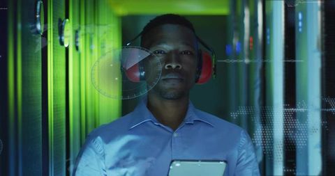 Data center technician monitoring server racks with tablet and red earmuffs, HUD diagnostics