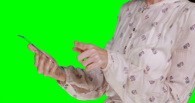 Unidentifiable person operates smartphone against green screen background, ideal for inserting custom video content or visual effects. Useful for technology themes, digital communication, mobile phone usage tutorials, online communication, video advertising, or digital marketing.