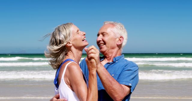A senior Caucasian couple enjoys a romantic moment on a sunny beach, with copy space. Their joyful expressions and affectionate pose convey a sense of love and companionship in their golden years.