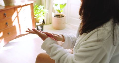 Relaxed Woman Massaging Wrist in Cozy Sunlit Room