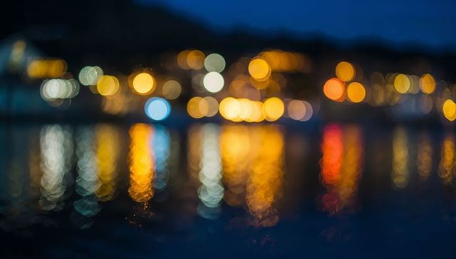 Glowing bokeh lights reflecting on harbor water at night