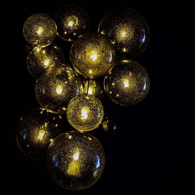 Golden glowing glass spheres and black background creates artistic and modern look. Perfect for creative projects, wall art, lighting decor advertisements, and festive occasions backgrounds.