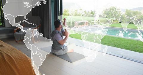 Man practicing yoga and meditation by glass doors overlooking pool with world map overlay