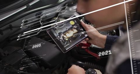 Automotive technician using tablet inspecting engine with augmented reality HUD diagnostics