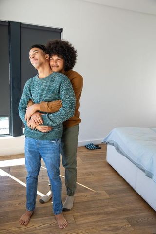 Diverse Male Couple Embracing Together in Cozy Bedroom Setting