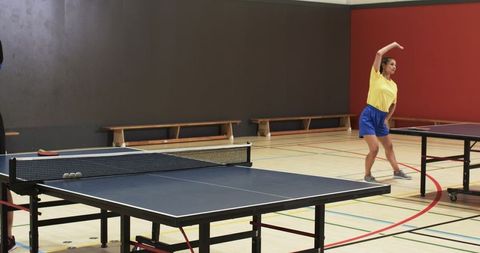 Woman Stretching on Court with Table Tennis Equipment in Gym