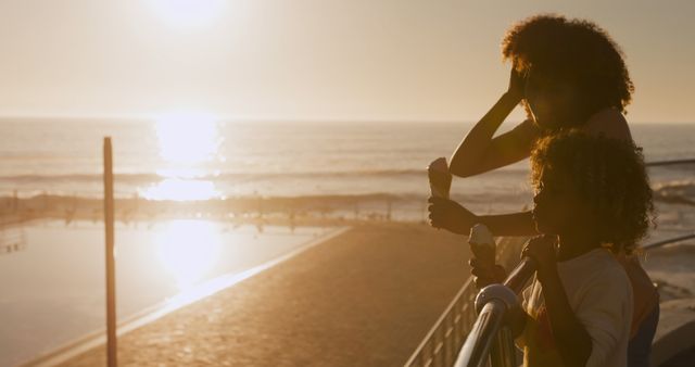 Mother and daughter enjoying ice cream at sunset on beach boardwalk - Download Free Stock Images Pikwizard.com