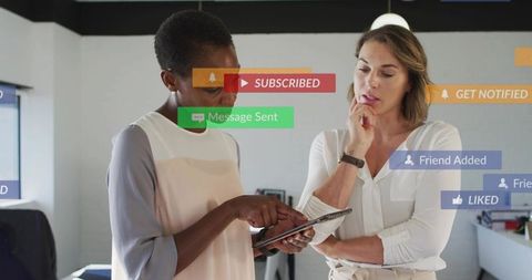 Two colleagues collaborating on tablet with social notifications digital marketing concept