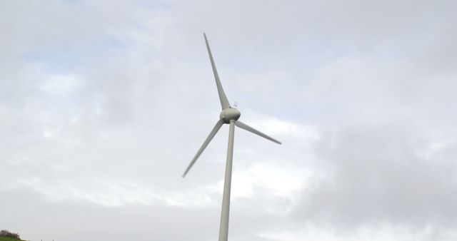 Single wind turbine standing tall against a cloudy sky represents renewable energy and sustainability. Ideal for environmental campaigns, eco-friendly product advertisements, and educational materials about clean energy and electricity generation.