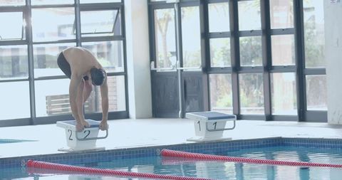 Male swimmer poised to dive off starting block