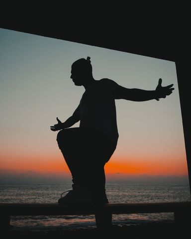 Silhouette of person embracing ocean dawn