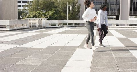 Diverse friends walking on rooftop terrace with striped tiles and urban skyline