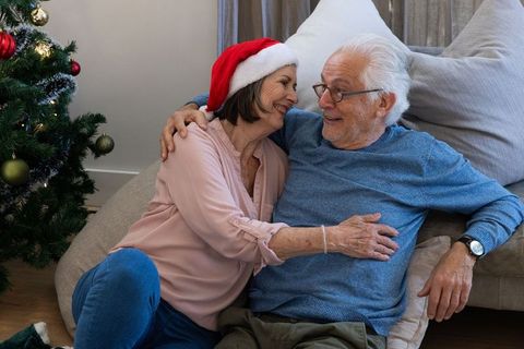 Senior couple embracing near christmas tree in cozy home