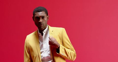 Confident Man in Bright Yellow Blazer Posing Against Red Background