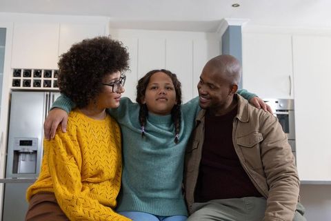 Diverse family hugging child on kitchen island, cozy modern home lifestyle