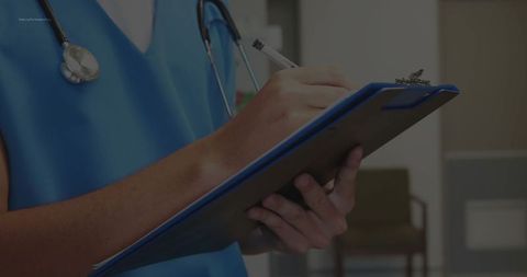 Healthcare Professional Writing Notes in Clinical Environment