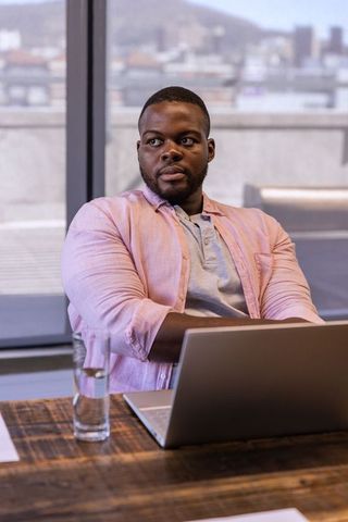 Confident Businessman Sitting in Urban Office with Laptop