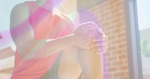 Fitness Man Performing Knee-to-Chest Stretch in Sunlit Urban Area