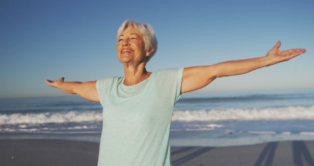 Happy senior caucasian woman smiling and widening arms on beach. Senior lifestyle, realxation, nature, free time and vacation.